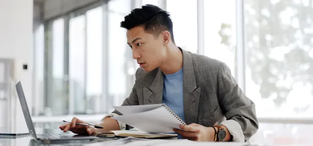 A business person in an open office working on a laptop.